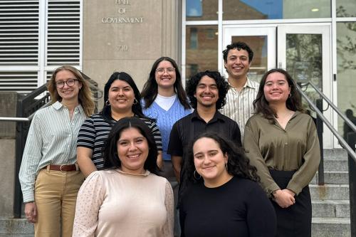 A group of smiling young people standing on a staircase outside the GW Hall of Government