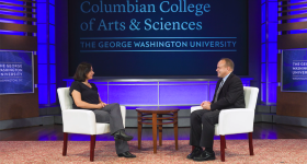 Dean Paul Wahlbeck seated on a stage across from Elizabeth Vaquera, with a Columbian College logo behind them